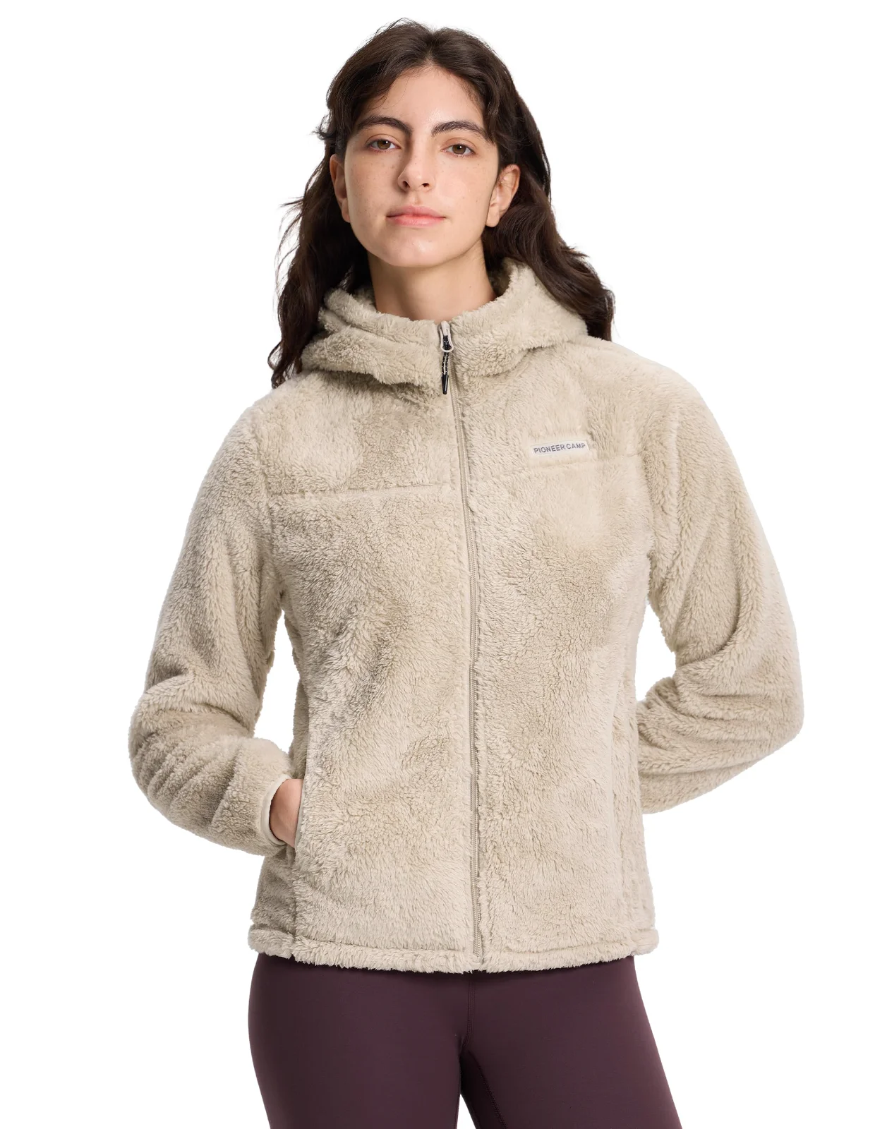 A woman in a cream sherpa fleece jacket, hands at her sides, the deep pile catching the light along the sleeve